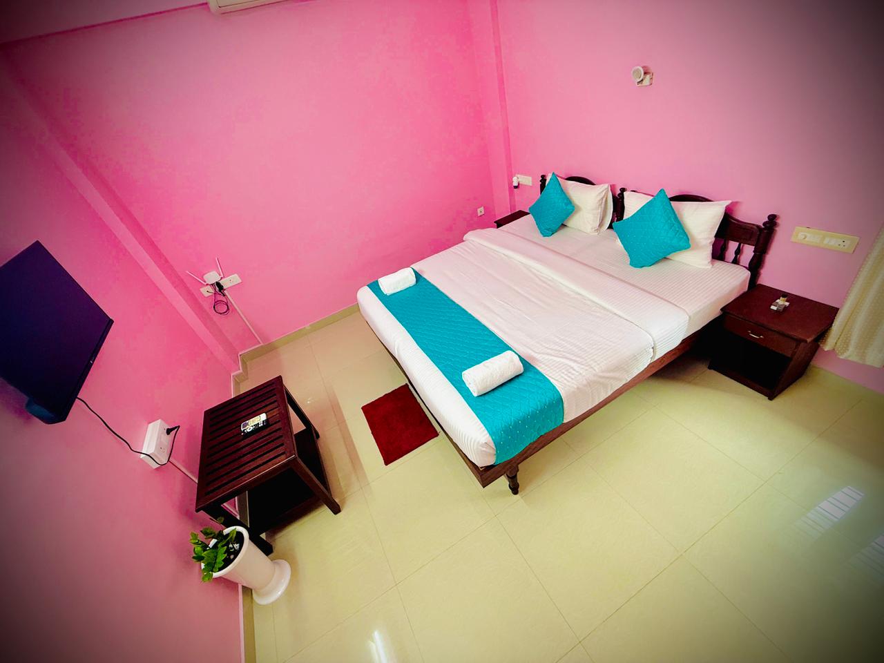 Twin bed room with turquoise accents, television, and luggage stand