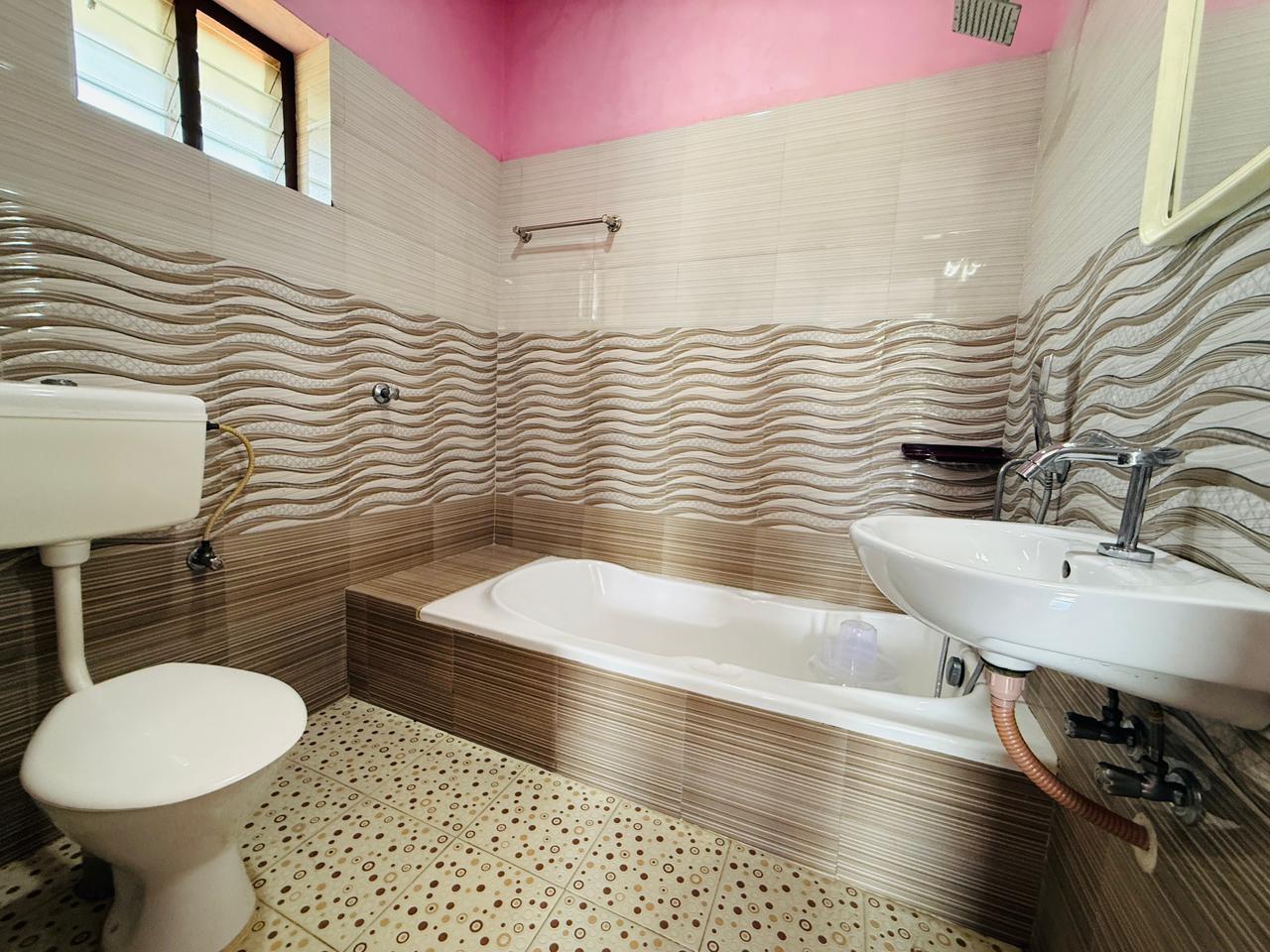 Bathroom with bathtub, sink, toilet, and patterned tiles